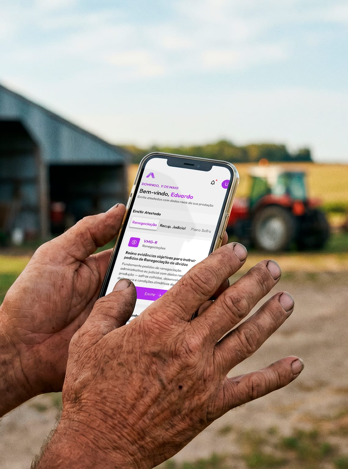 Produtor rural segurando o celular com o app da Agromai, lavoura de soja ao entardecer ao fundo